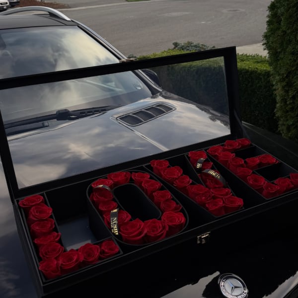 Red roses arranged in a black gift box spelling "LOVE"