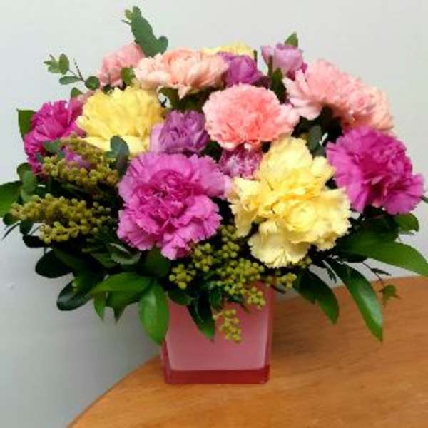 Colorful bouquet of carnations in a pink square vase