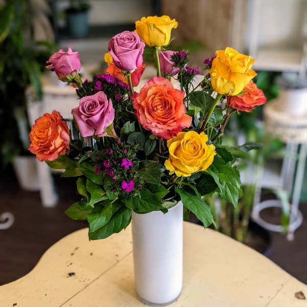 Mixed roses in pink, orange, and yellow in a white vase
