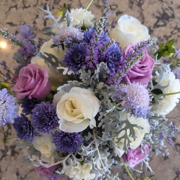 Round bouquet of white and lavender roses with purple mums and silver-toned foliage