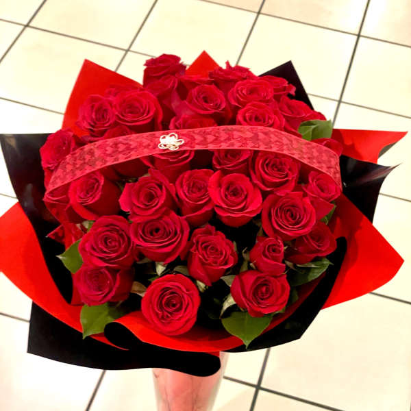 Bouquet of red roses wrapped in red and black paper in a clear vase