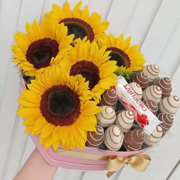 Sunflowers arranged with chocolate candies in a pink box