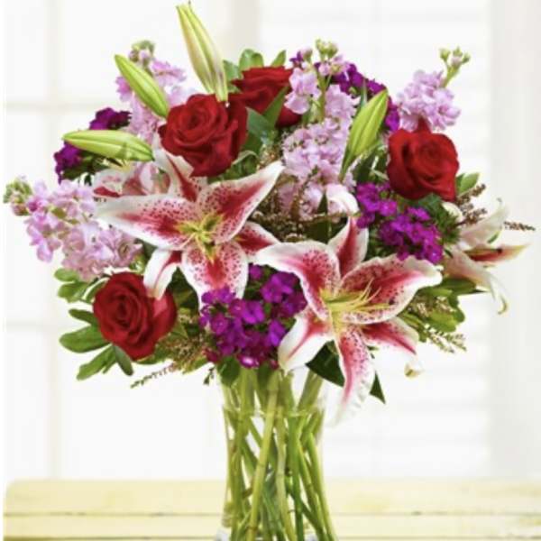 Bouquet of red roses and pink lilies in a clear glass vase
