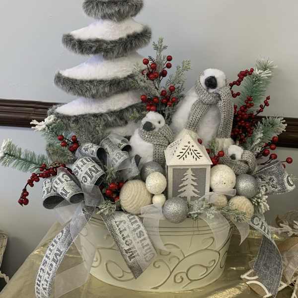 Winter holiday centerpiece with a faux tree, penguins, and silver ribbons