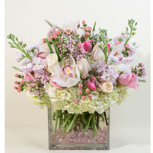 Low pink and white flower arrangement with orchids and roses in a square glass vase