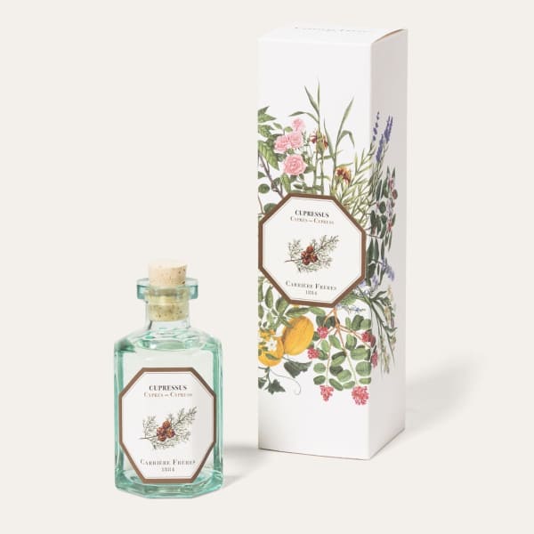 Glass bottle of cypress fragrance beside a floral-patterned box