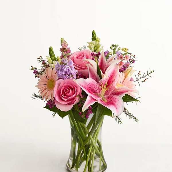 Pink roses and lilies in a clear glass vase