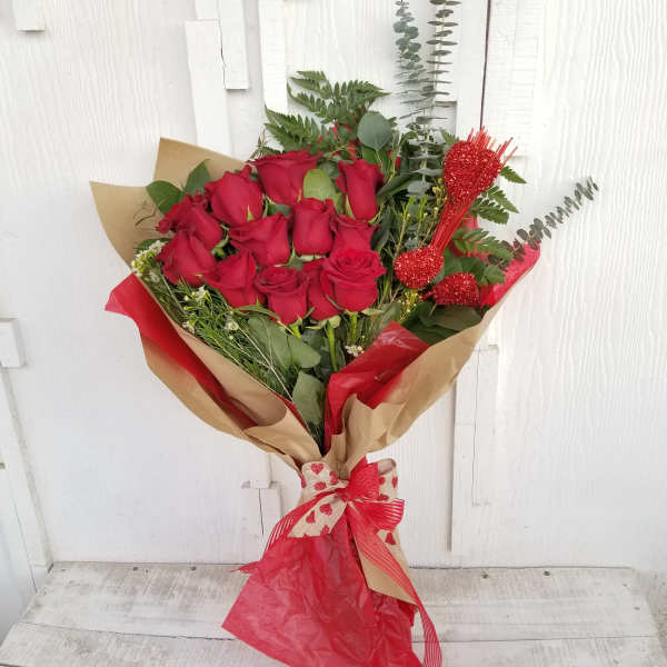 Bouquet of red roses wrapped in brown and red paper with a ribbon