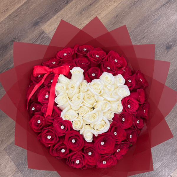 Round bouquet of red roses with a white heart of roses, wrapped in red paper with jewel accents