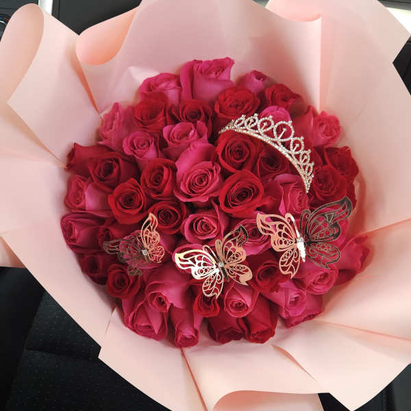 Bouquet of pink and red roses with butterfly decorations and a tiara