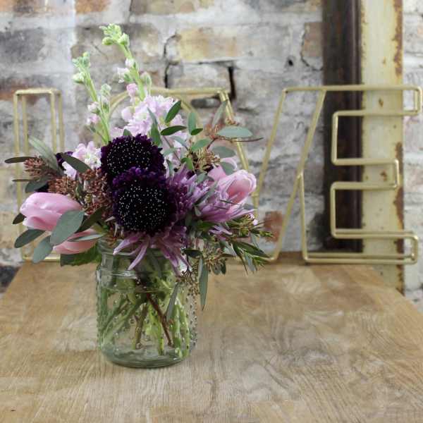 Pink and purple bouquet in a clear glass jar vase