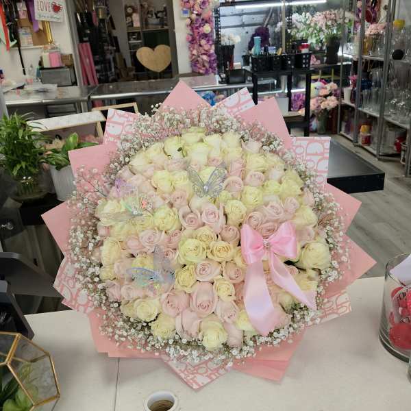 Large bouquet of pale pink and cream roses with a pink ribbon