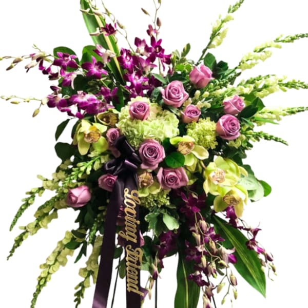 Large bouquet of purple orchids, pink roses, and green hydrangeas with a ribbon
