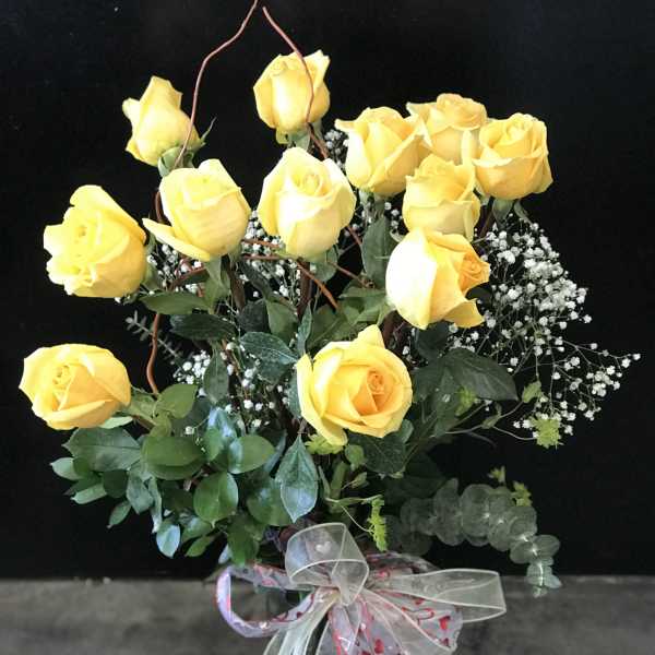 Bouquet of yellow roses with baby's breath in a glass vase