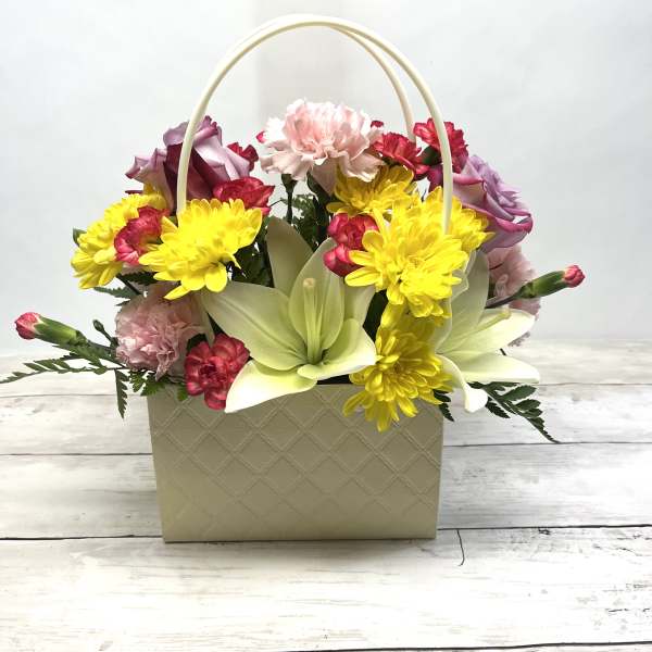 Basket arrangement with yellow daisies, pink carnations, and pale lilies