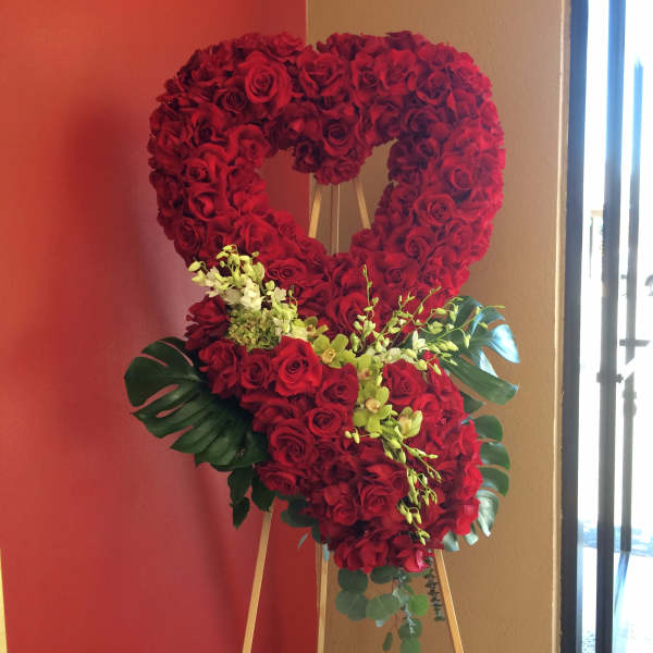 Heart-shaped red rose arrangement on an easel with green accents