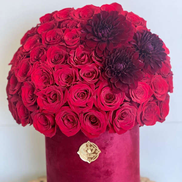 Red rose bouquet in a velvet hatbox with dark burgundy flowers