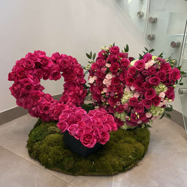 Pair of pink rose heart arrangements on a moss-covered base