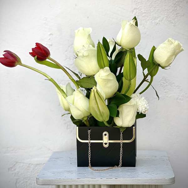 White and red tulips arranged in a black handbag-shaped box