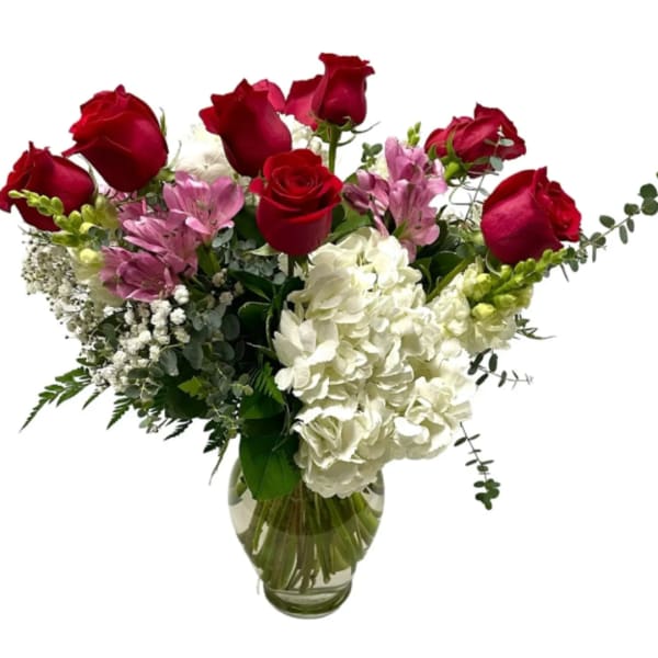 Red roses and white hydrangeas in a glass vase with pink accents