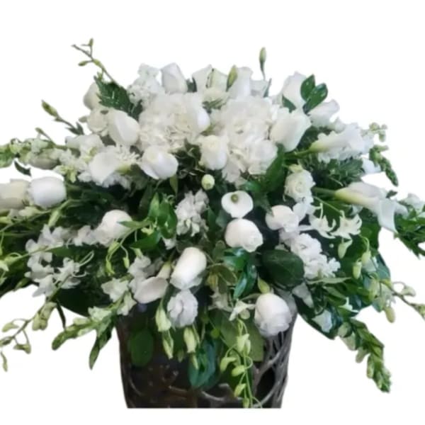 White floral arrangement in a dark vase with trailing greenery