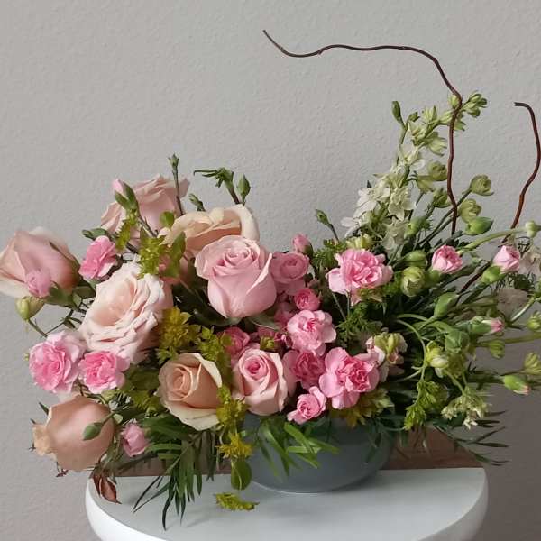 Pink and peach roses with small pink blooms in a low gray bowl