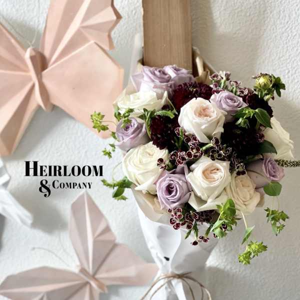 Bouquet of white and lavender roses with dark burgundy accents
