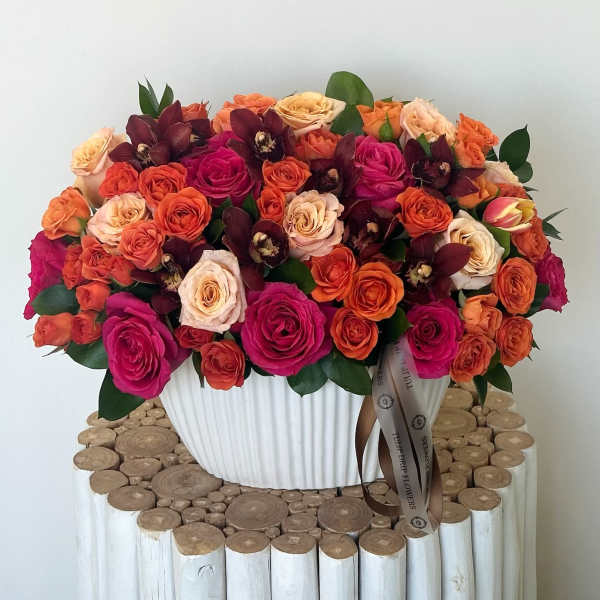 Large bouquet of pink, orange, and cream roses in a white vase