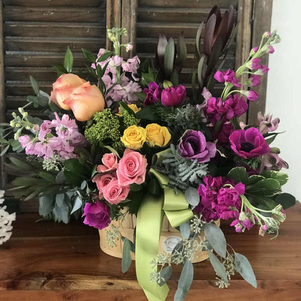 Mixed bouquet in a basket with roses, tulips, and purple blooms