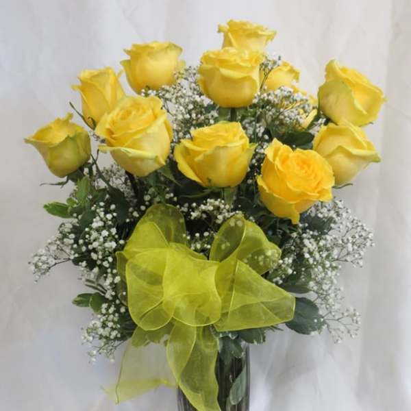 Yellow roses in a clear glass vase with a yellow ribbon