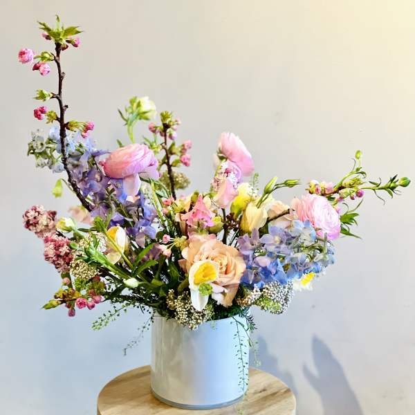 Pastel mixed flower arrangement in a white cylindrical vase