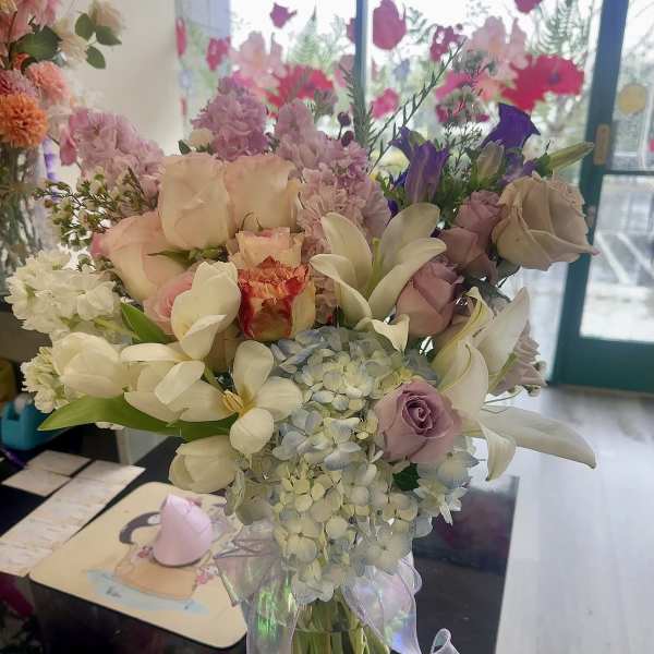 Pastel bouquet of roses, lilies, and hydrangeas in a glass vase