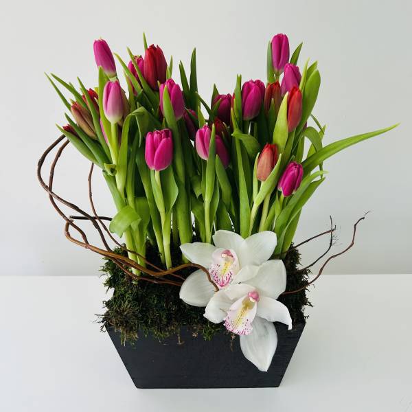 Pink tulips and white orchids in a black rectangular planter