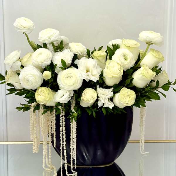 White floral arrangement in a dark vase with trailing white strands