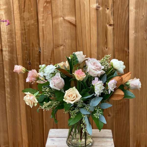 Bouquet of pale roses and white blooms in a glass vase