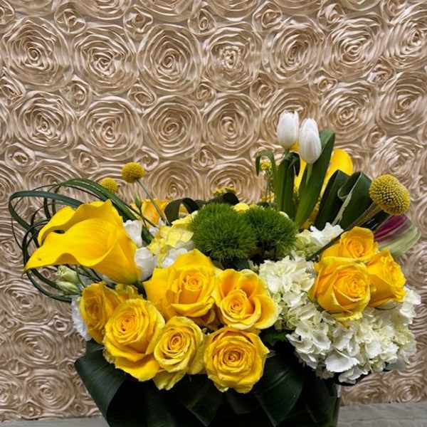 Yellow roses and white flowers arranged in a black container