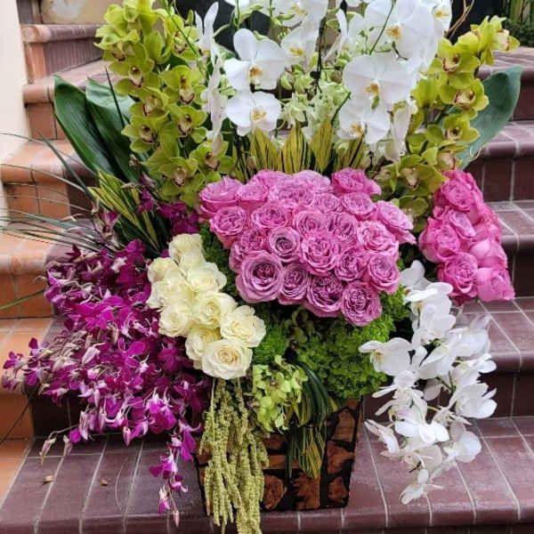 Large floral arrangement with white orchids, pink roses, and purple orchids