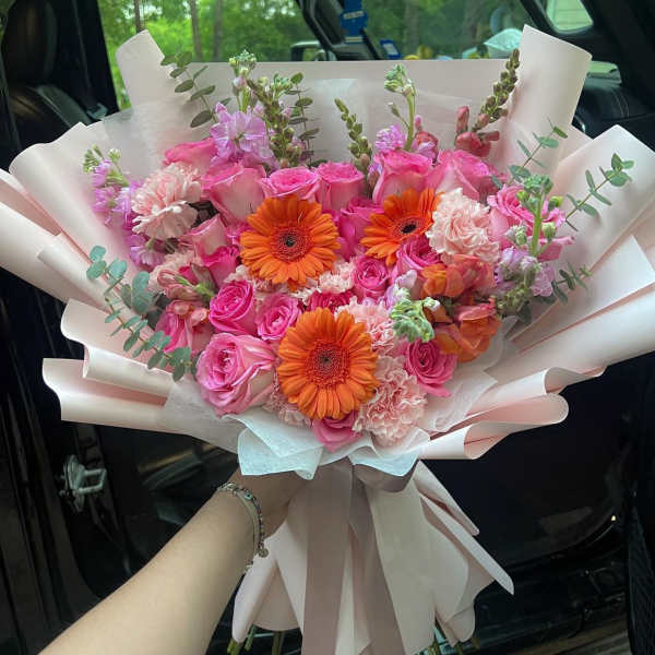 Pink rose bouquet with orange gerbera daisies and pale wrapping