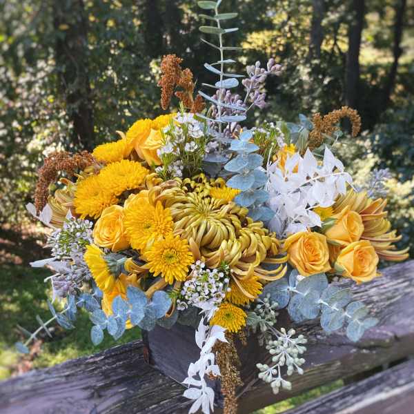 Yellow bouquet with roses and chrysanthemums in a dark box