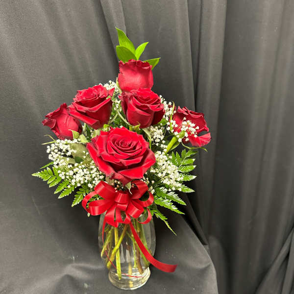 Red roses in a clear glass vase with a red ribbon bow