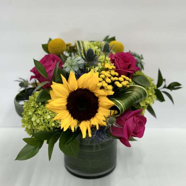 Sunflower and pink rose arrangement in a green vase