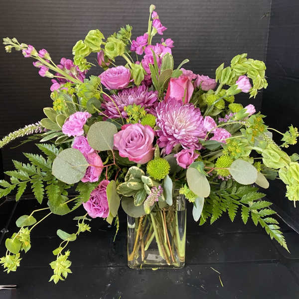 Pink mixed bouquet in a clear glass vase with green accents