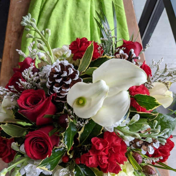 Bouquet of red roses, white calla lilies, and pinecones