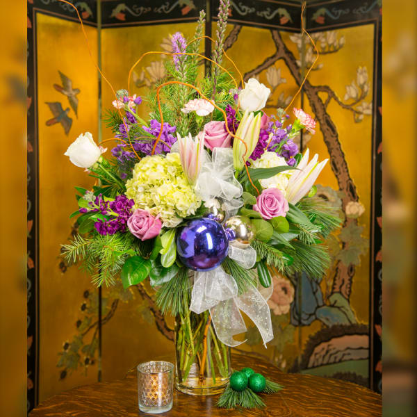 Tall mixed bouquet in a glass vase with purple, pink, white, and yellow flowers