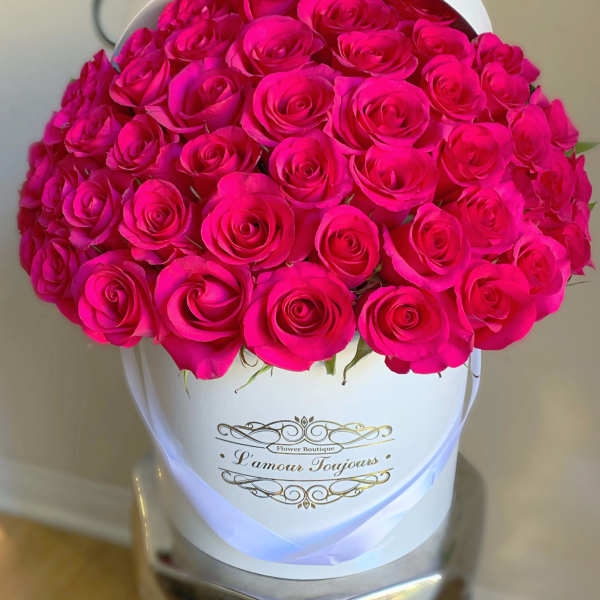 Hot pink roses arranged in a white hatbox with gold lettering