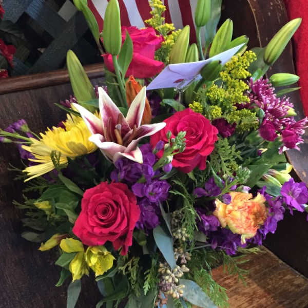 Mixed bouquet of roses, lilies, and chrysanthemums in a glass vase
