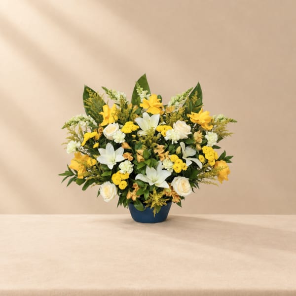 Yellow and white floral arrangement in a blue vase