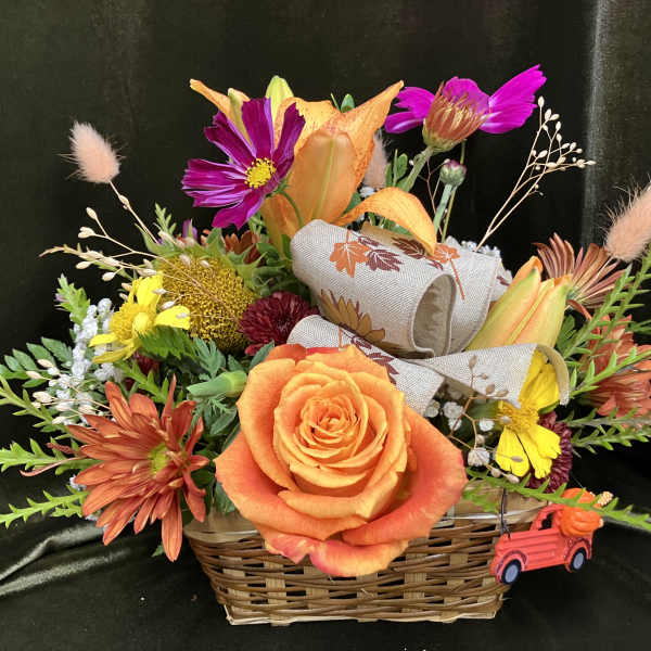 Basket arrangement with orange roses, lilies, and mixed fall flowers