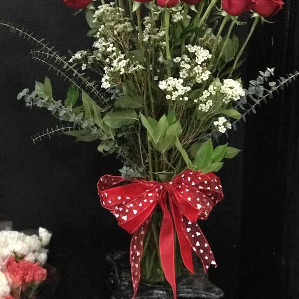 Bouquet of red roses with white filler flowers and a red heart ribbon