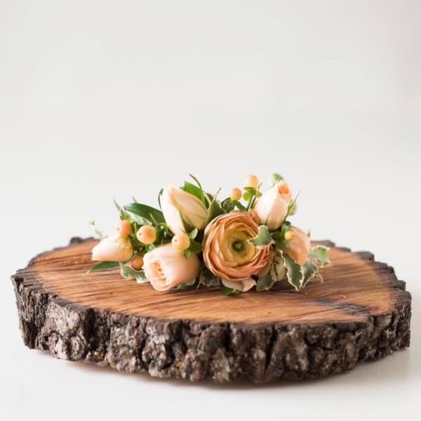 Peach floral arrangement on a wood slice base